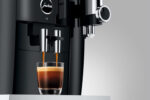 Jura S8 Kaffeevollautomat mit Touchscreen brüht zwei Espresso aus dem oberen Schlitz in ein Glas Espresso.