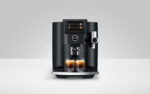 Jura S8 Kaffeevollautomat mit Touchscreen und Zwei Espressogläsern darunter, frontale Bedienung, modernes schwarzes Design.