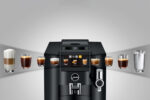 Jura S8 Kaffeevollautomat mit Touchscreen, zentrale Bedieneinheit, milchhaltige Getränke neben Gläsern und Wasser, elegant schwarzes Gehäuse.