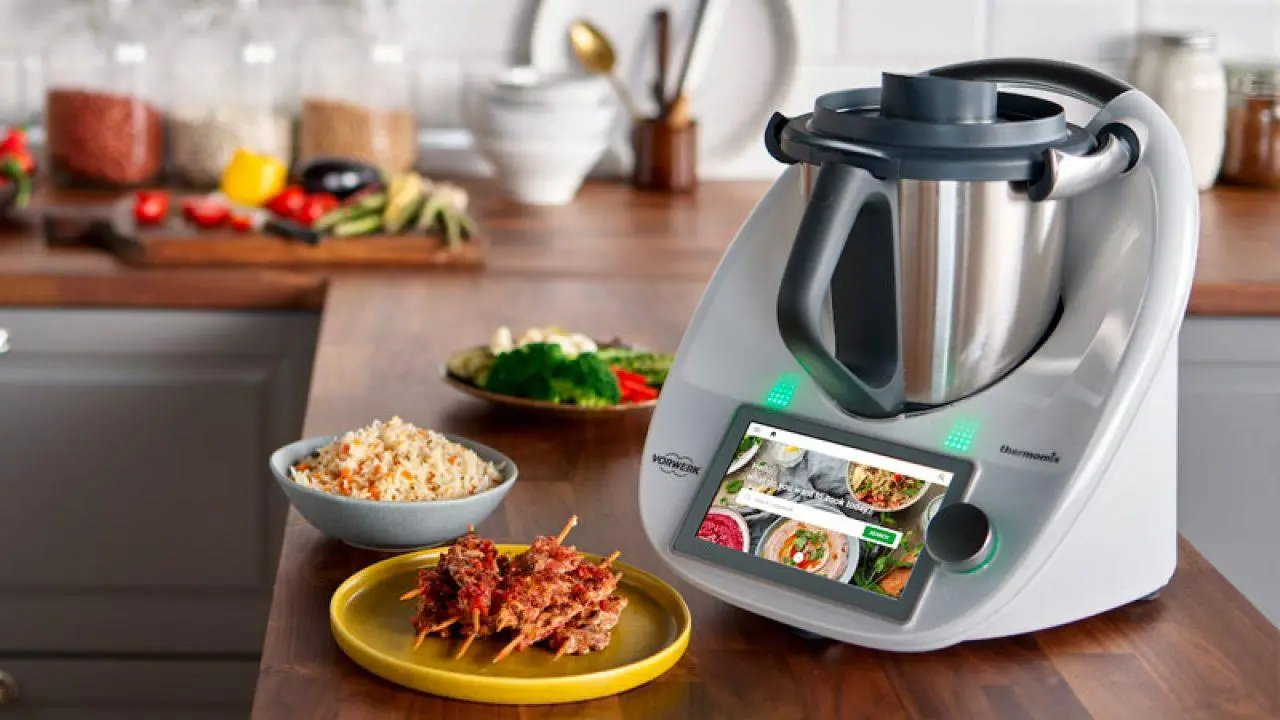 Standmixer mit Touchscreen-Bedienung auf moderner Küchenarbeitsplatte; daneben Teller mit Essen.